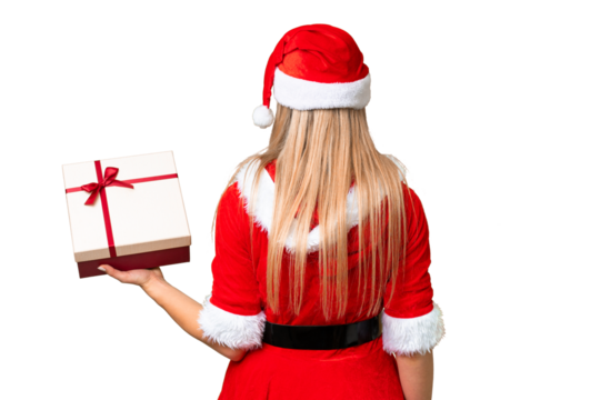 Young blonde woman with christmas hat and holding a gift over isolated chroma key background in back position - Powered by Adobe