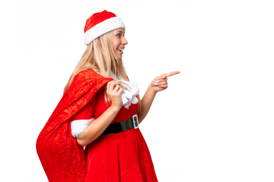 Young blonde woman with christmas hat over isolated chroma key background pointing to the side to present a product