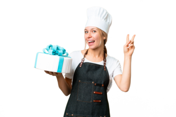 Young pastry blonde woman with a big cake over isolated chroma key background smiling and showing victory sign