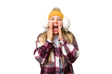 Young pretty blonde woman wearing winter muffs over isolated chroma key background shouting and...