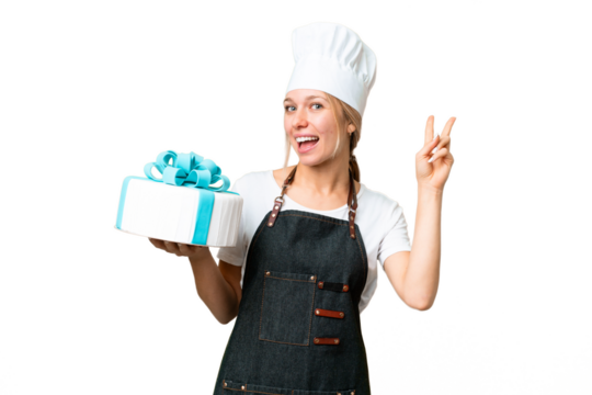 Young pastry blonde woman with a big cake over isolated chroma key background smiling and showing victory sign