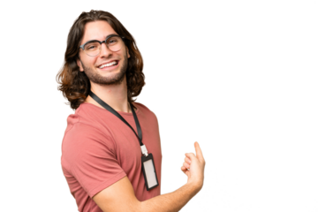 Young handsome man with ID card over isolated background pointing back