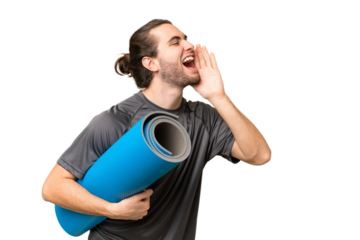Young sport man going to yoga classes while holding a mat over isolated background shouting with mouth wide open to the side