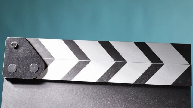 Closeup of a clapboard clapping, chalk particles dispersing in the air, marking a movie take