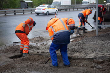 Laying asphalt on road. Repair of road. Worker with shovel.