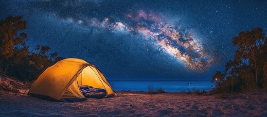 Illuminated tent on beach, Milky Way backdrop, tranquil night