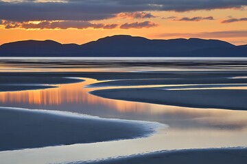 Fototapeta premium Golden hour water reflections over sand at low tide. Mountains at dusk in the background. Nature wallpaper