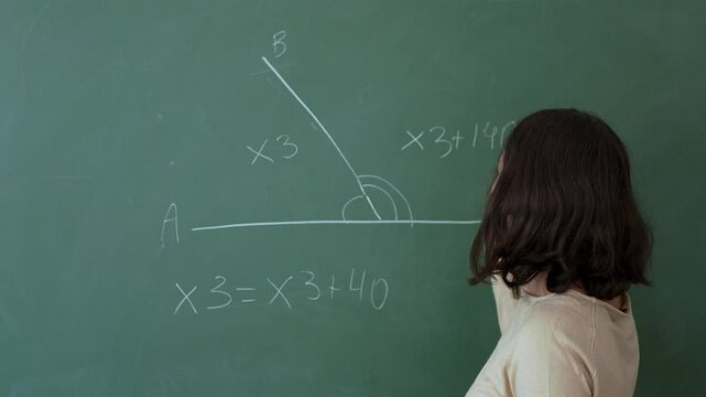 A teenage girl solves a math problem on the board during a math lesson