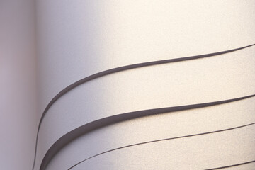 Paper background with satin pearlescent texture. Glossy folded wavy strips, layered surface in pale...