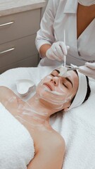 Female beautician cleansing skin of young woman with foaming cleanser, cosmetology procedure in...