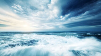 Obraz premium Ocean waves under a cloudy sky with sunlight breaking through.