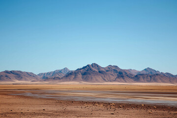 a distant mountain range above a flat, dry plain where water once flowed.