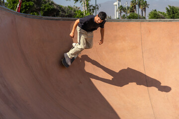 young man in black t-shirt skating at a skate park in a sunny day. Arinaga. Gran Canaria. Canary...
