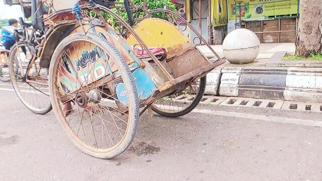 Cinematic shot of a colorful vibrant paintings decorated rickshaw existingly parked among motorcycles in Pemalang, Indonesia. Old School transportation mode concept 