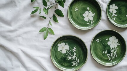 A white bedsheet with green plates and a plant on it.