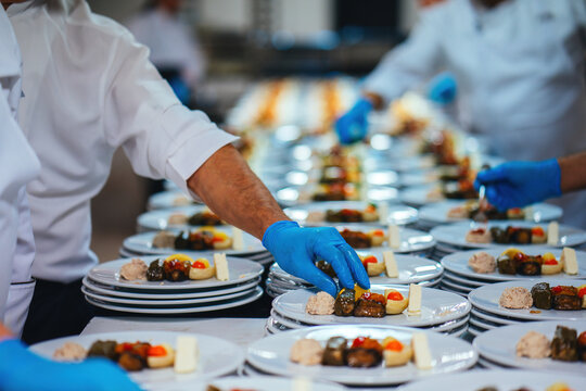 A long table prepared by a catering company for a special invitation. Plates are being filled one by one for service.