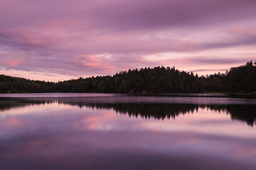 Vibrant sunset over a tranquil lake near Gothenburg with reflections on calm water