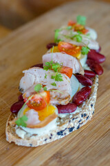 Close up of bruschetta with egg, chicken, tomato, red beans and basil