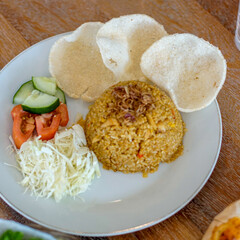 Fried rice with vegetables and rice crackers on a white plate