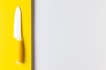 Minimalist Yellow and White Ceramic Knife on Modern Two-Tone Background