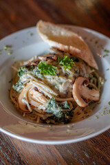 Close up of Italian creamy pasta with mushrooms, vegetables and bread
