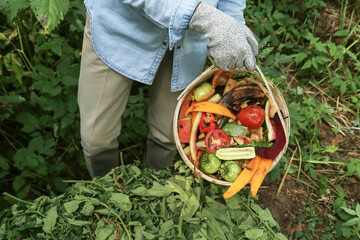 Zero waste, composting concept. Compost heap pile with bio waste. Farmer hands put weeds grass...