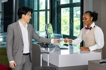 Asian businessman passenger is receiving boarding pass from the airline ground crew at check in...