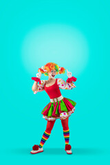 Funny female clown pointing up at blank template copy spase for advertising, posters, greetings, invitations. Entertainer as Joker in a suit and wig, with clown whiteface makeup