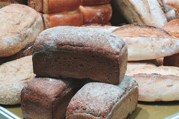 A stack of bread with a white powder on top. There are many other loaves of bread in the background