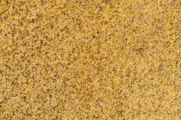 yellow-brown granite surface with small black and gray inclusions. background and pattern.