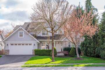 Two story stucco luxury house with nice spring blossom landscape in Vancouver, Canada, North America. Day time on April 2025.