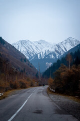 Fototapeta premium Kyrgyzstan Scenic Mountain Road Leading to Snow-Capped Peaks in Autumn