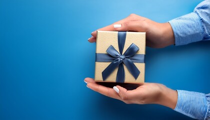 thoughtful gift giving concept with hand holding gift box on blue background