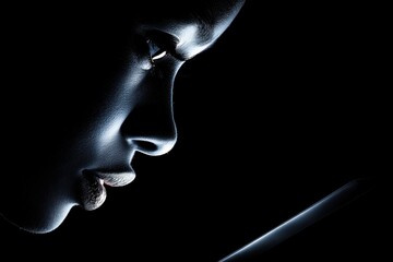 A dramatic close-up of a woman's face in deep shadow, highlighted by a single light source, holding a phone creating a modern, artistic, and mysterious image.