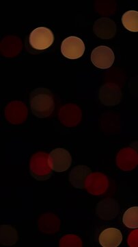 Una toma de cerca de varias luces de colores en forma de c&iacute;rculos en movimiento en la oscuridad. Desenfoque, efecto Bokeh. Video vertical.