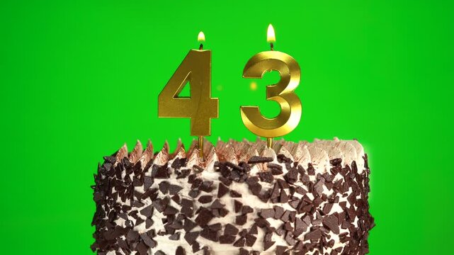 Lighting candles on Chocolate birthday cake on green chroma key background with number forty-three golden candles. Celebration Birthday cake for 43 years.