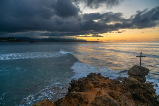Cross on rocks on promontoriy in Tartane on Martinique with Dominica in distance on horizon