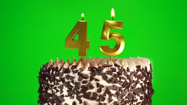 Lighting candles on Chocolate birthday cake on green chroma key background with number forty-five golden candles. Celebration Birthday cake for 45 years.