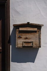 Old weathered wooden post box on the white wall