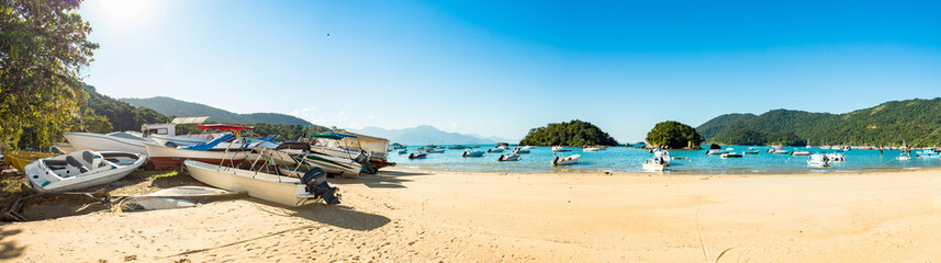 Panoramic blue and green beach vacation in the village of Abraao with boats on a sunny day, on the tropical island Grande, Rio de Janeiro, Brazil, South America.