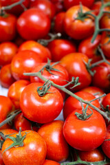 A bunch of ripe red tomatoes are piled on top of each other. The tomatoes are all different sizes and are arranged in a way that they are all visible. Concept of abundance and freshness