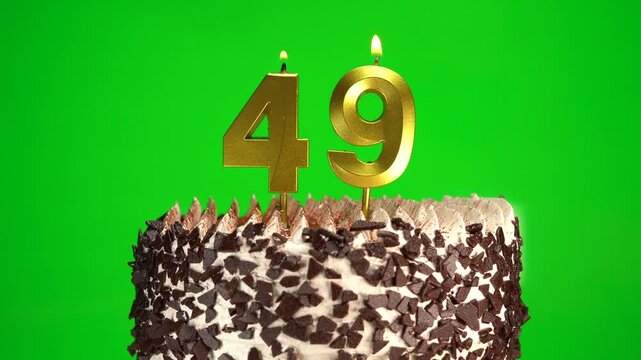 Lighting candles on Chocolate birthday cake on green chroma key background with number forty-nine golden candles. Celebration Birthday cake for 49 years.