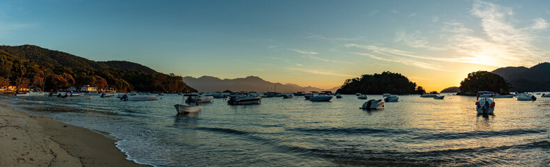 Boat trip on vacation in Ilha Grande with stop at Abraao beach, sunset and colorful sky and taxi boat moored, panoramic view in the south of Rio de Janeiro, Brazil.