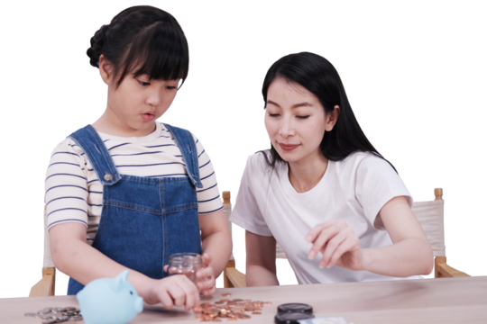Smiling Asian daughter and mother putting coins into piggy bank for saving money for the future on wooden table. Child educational for homeschooling concept - Powered by Adobe