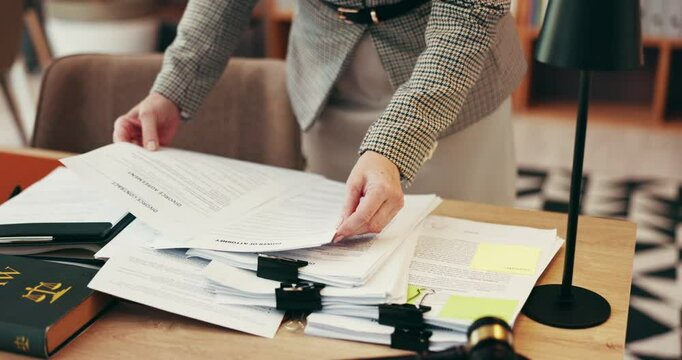 Person, hands and lawyer with documents for legal advice, testimonial or statements at office desk. Closeup, employee or attorney with paperwork for lawsuit, regulations or case notes at law firm