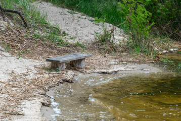 Sandy beach with spring view on picturesque river on natural park. Trees and plants water edge with...