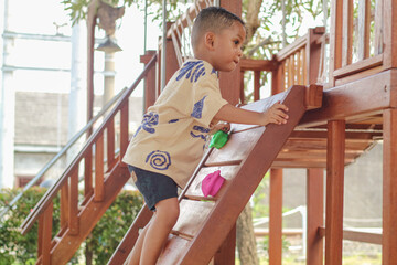 Obraz premium Little boy climbing up brave at playground