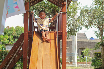 Asian child smiling playing on slider bar toy outdoor playground, happy preschool little kid having...