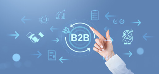 Businesswoman touching B2B interface with digital icons on blue background.