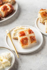 Traditional Easter hot cross buns on white plate with butter on light gray background. Delicious Easter breakfast